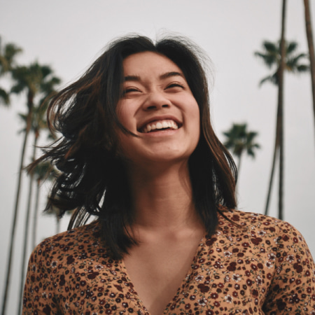 Female outside with palm trees shows her new smile